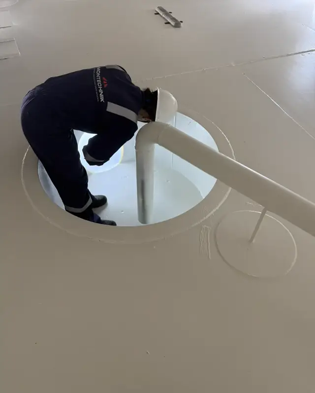 Colaborador entrando pela boca de visita de um tanque