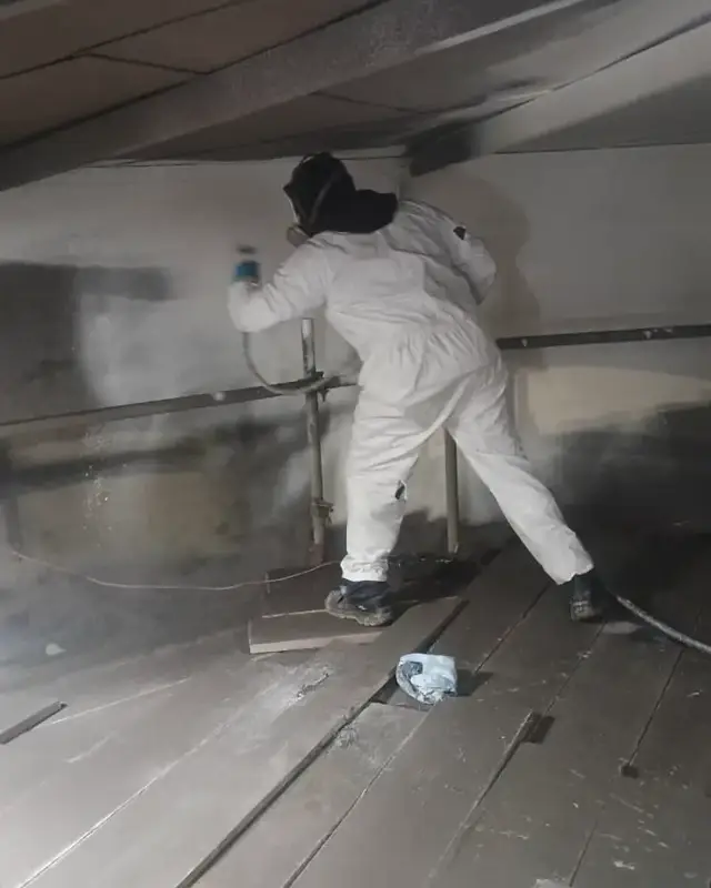 Colaborador com macacão de proteção dentro de estrutura metálica