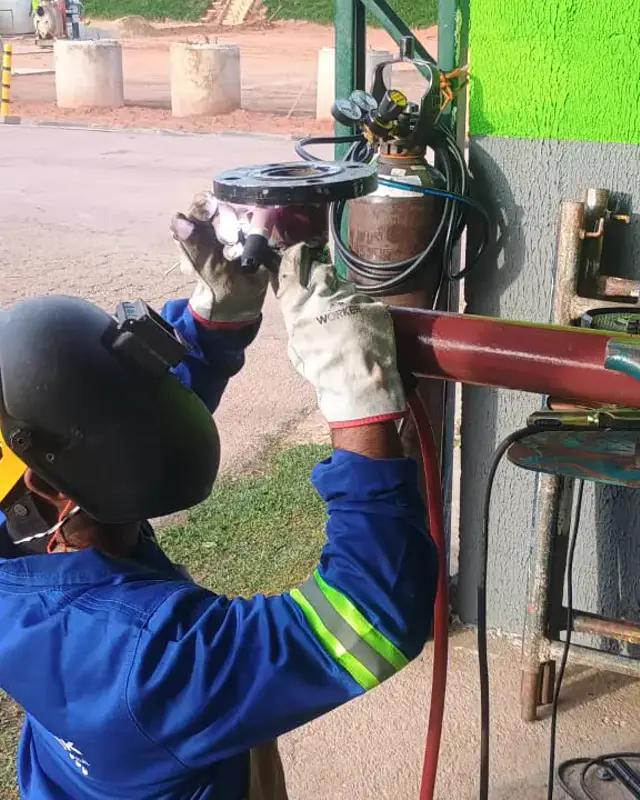 Colaborador com esmerilhadeira em equipamento industrial